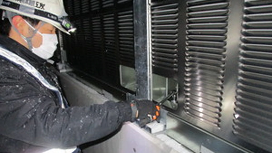 点検口付きパネルを設置後 道路側から、遮音壁背面のアンカーボルトを点検している様子の画像